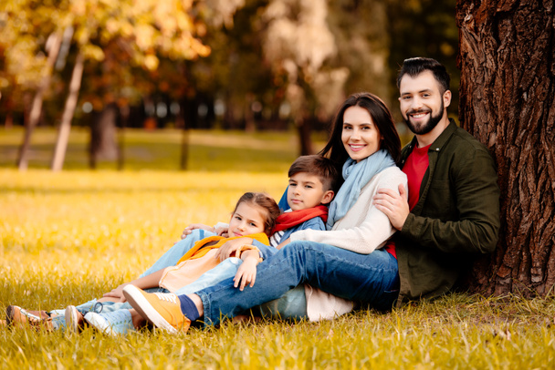 Onnellinen perhe nojaa puuhun
 - Valokuva, kuva