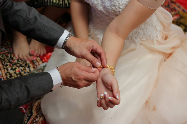 Groom a mis le bracelet en or sur le poignet de la mariée. Notion de mariage
 - Photo, image