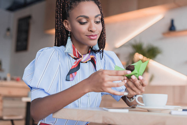 african american woman eating muffin in cafe - Foto, afbeelding