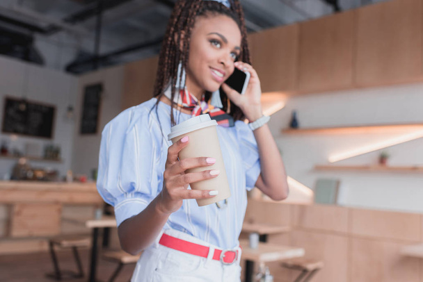Afrikaanse Amerikaanse vrouw praten over telefoon in café - Foto, afbeelding
