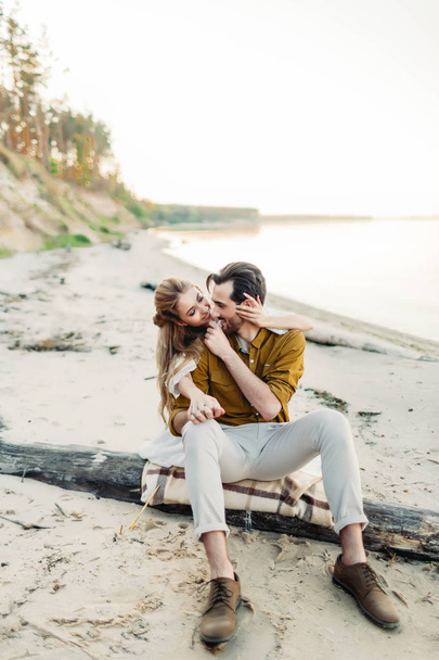 Ein junges Paar amüsiert sich am Strand und umarmt sich. schöne Mädchen umarmen ihren Freund von hinten. Hochzeitsmarsch. ein frisch vermähltes Paar schaut einander an. Kunstwerk - Foto, Bild