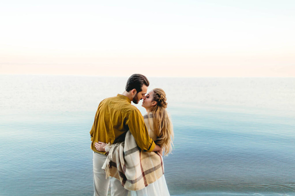 A beautiful couple is embracing on the sea background. Moment before the kiss. Romantic date on the beach. View from the back. Wedding. Artwork - Foto, imagen