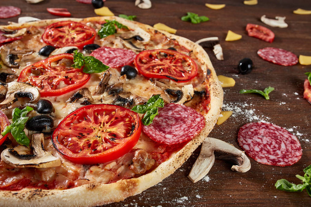 Closeup of pizza with salami, tomatoes and olives - Φωτογραφία, εικόνα