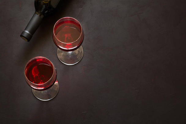 Δύο wineglasses με κόκκινο κρασί και ψέματα μπουκάλι στο καφέ ξύλινα d - Φωτογραφία, εικόνα