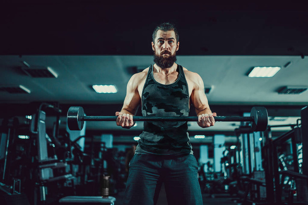 Muscular bodybuilder guy doing exercises with dumbbell in gym - Fotó, kép