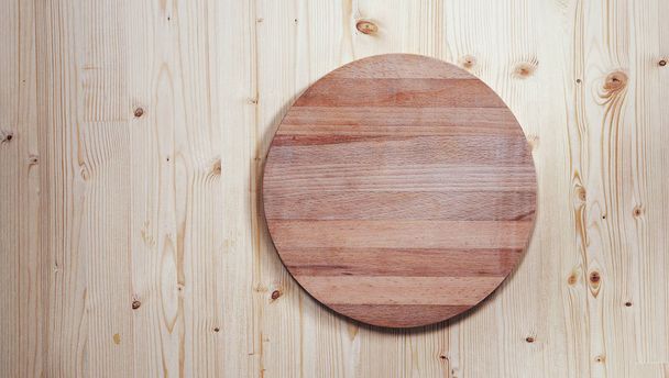 empty round wooden board for cutting on a wooden background - Fotografie, Obrázek