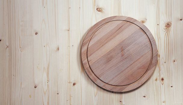 empty round wooden board for cutting on a wooden background - Foto, imagen