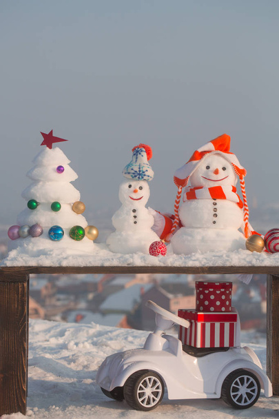 Toy car with present boxes on snowy background - Fotó, kép