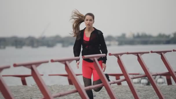 Sportswoman jogging outdoors in a sports wear at cloudy autumn day - Video, Çekim