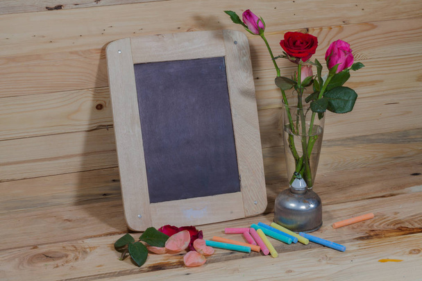 slate, pastel and roses on the pinewood table - Photo, Image