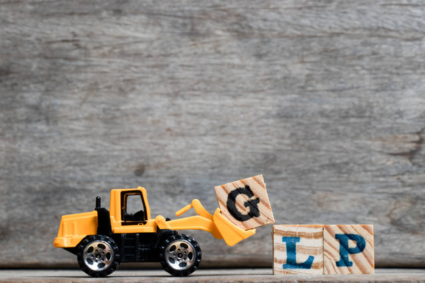 Gele kunststof bulldozer houden letter G te voltooien woord Glp (afkorting Good Laboratory Practice) op houten achtergrond - Foto, afbeelding