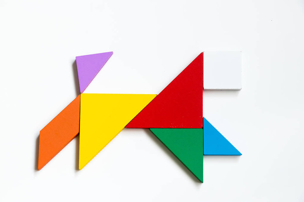 Colorful wood tangram puzzle in running dog shape on white background - Photo, Image