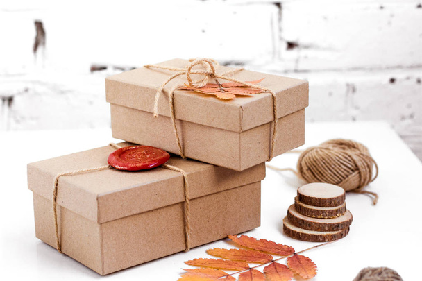 Handmade gifts wrapped in craft paper and dry leaves on the white background - Fotoğraf, Görsel
