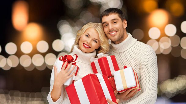 happy couple in sweaters holding christmas gifts - Fotó, kép