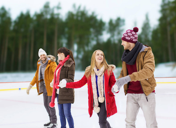 friends holding hands on outdoor skating rink - Foto, afbeelding