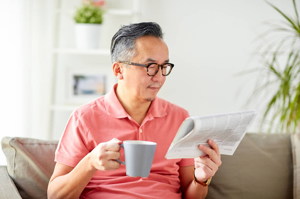 man drinking coffee and reading newspaper at home - Фото, зображення