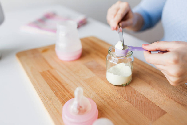 hands with jar and scoop making formula milk - Foto, Imagem