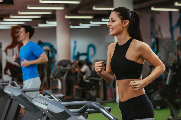 Girl running on treadmill in gym - Foto, afbeelding