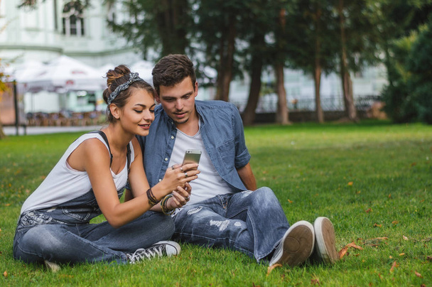 Young happy couple sitting on grass  - Zdjęcie, obraz