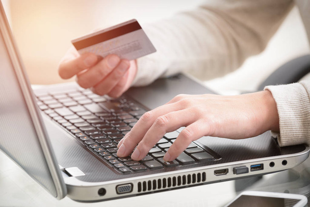 Womans hand holding credit card over laptop - Foto, Bild