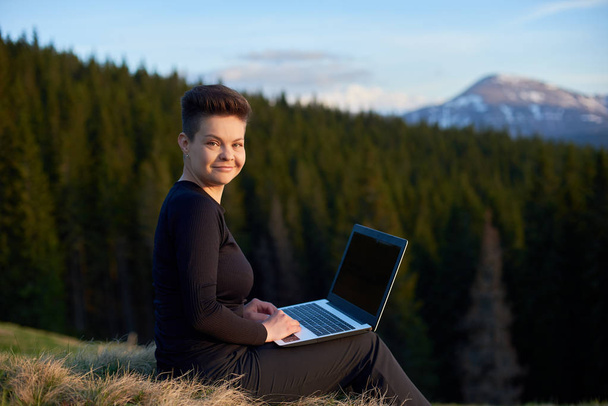 Молодая женщина использует ноутбук на открытом воздухе
 - Фото, изображение