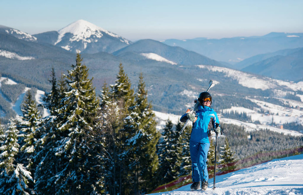 Vrouwelijke skiër permanent op de top van een heuvel  - Foto, afbeelding