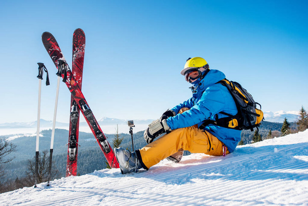 σκιέρ που κάθεται κοντά τον εξοπλισμό του σκι - Φωτογραφία, εικόνα