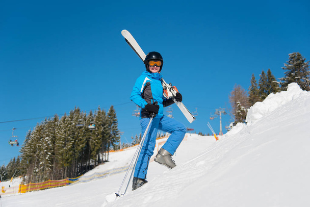 женщина лыжник, несущая свои лыжи
  - Фото, изображение