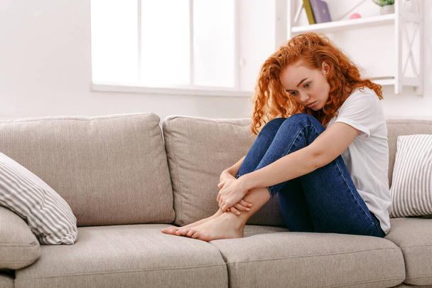 Mujer pelirroja triste pensando en sofá beige
 - Foto, Imagen