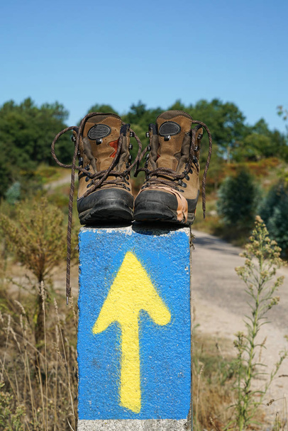 Broken walking shoes on the top of a waymark along the Way of St. James, Spain, Europe - Photo, Image