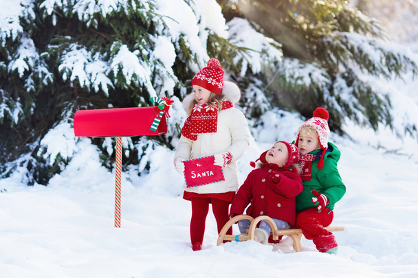 Τα παιδιά με γράμμα στον Άγιο Βασίλη στο Χριστουγεννιάτικο αλληλογραφίας πλαίσιο στο χιόνι - Φωτογραφία, εικόνα