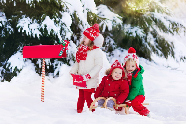 Children with letter to Santa at Christmas mail box in snow - Фото, зображення