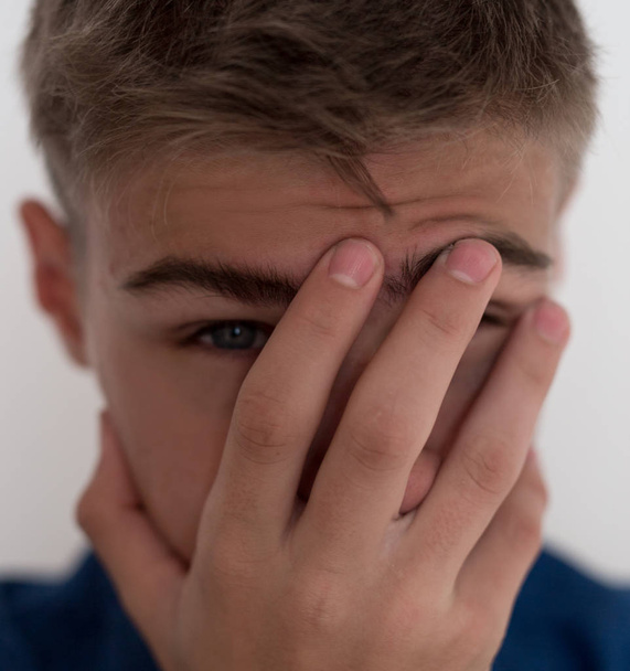 a teen boy upset, covers his face with his hands. close-up of fa - Photo, Image
