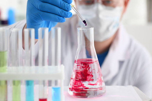 Ein Chemiker hält ein Reagenzglas in der Hand, in dem eine Flüssigkeit überläuft  - Foto, Bild