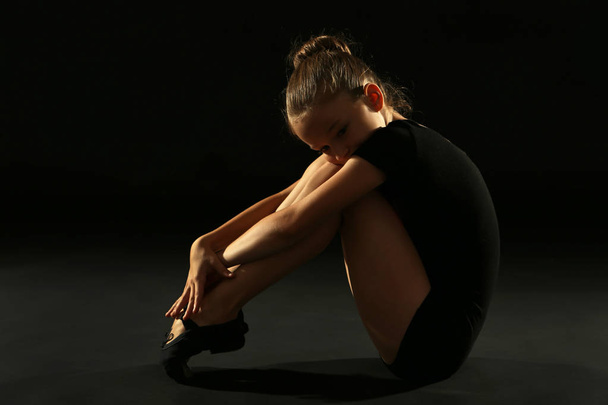Young girl gymnast on black background - Fotó, kép