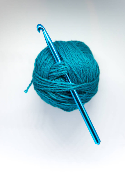 A beautiful wool yarn with a crochet needle on a white background. Hand craft tools. - Fotografie, Obrázek