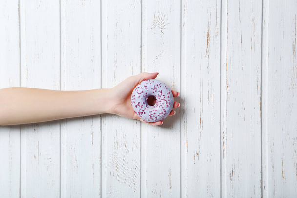Female hand holding sweet donut  - Foto, afbeelding