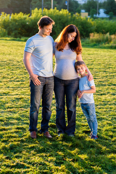 Gelukkige familie van drie staande in park - Foto, afbeelding
