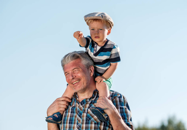 Grandfather carries grandson on shoulders - Photo, Image
