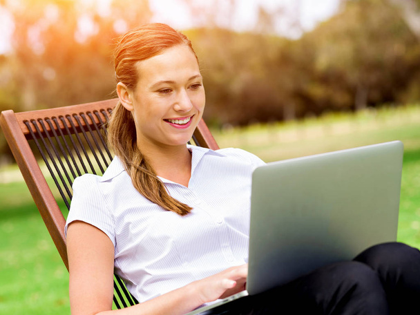 Young business woman sitting in park and working with laptop - Valokuva, kuva
