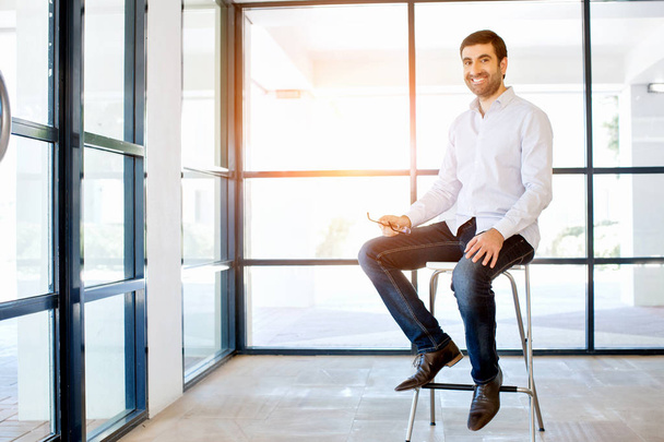 Young business man sitting on a stool in office - Photo, image