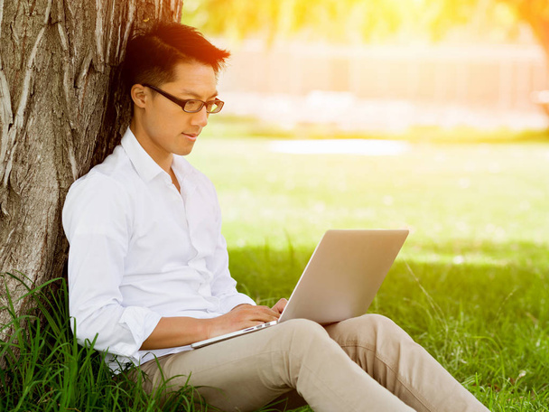 Young businessman using laptop while sitting outdoors - Photo, Image