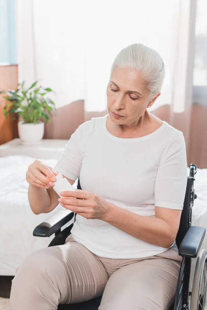 Frau im Rollstuhl nimmt Medikamente - Foto, Bild