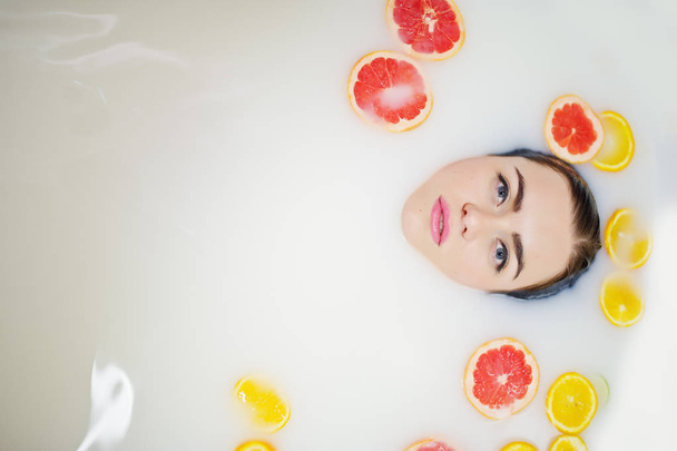 Το σέξι κορίτσι μελαχρινή στο μπάνιο με γάλα και φρούτα. Νέων β - Φωτογραφία, εικόνα