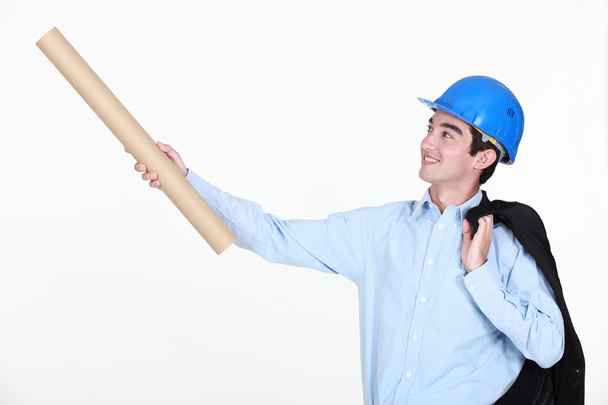 Young engineer holding up a rolled-up drawing - Photo, Image