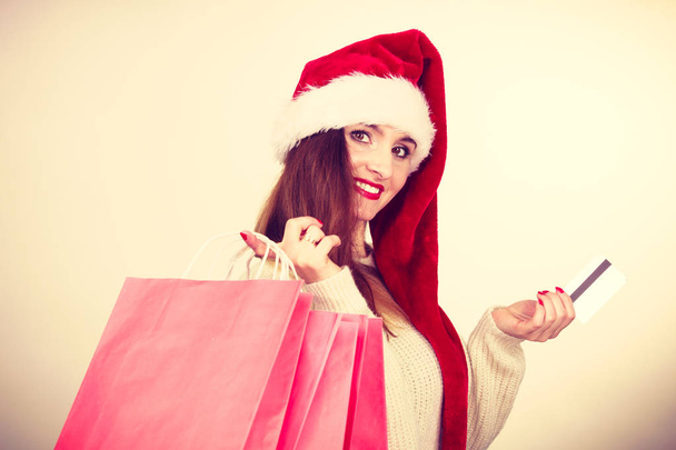 woman in Christmas hat holds credit card and shopping bags. - Fotó, kép