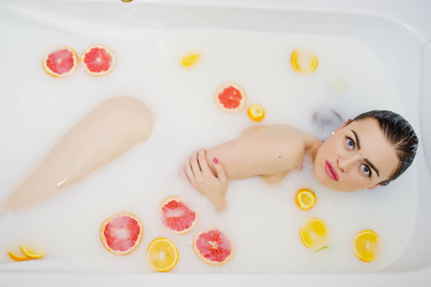 Sexy brunette girl at the bathroom with milk and fruits. Youth b - 写真・画像