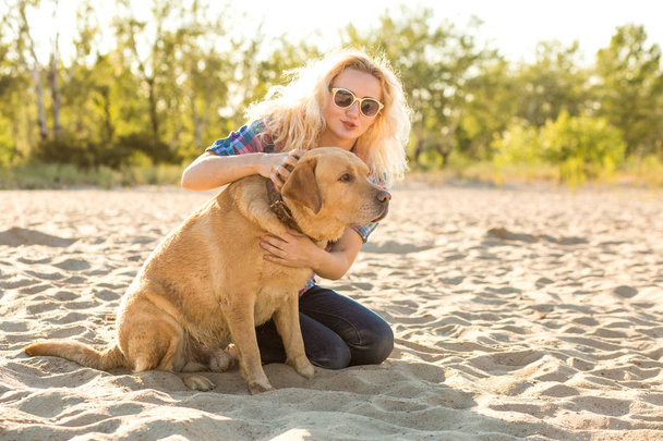Молодая женщина со своей собакой на пляже
 - Фото, изображение