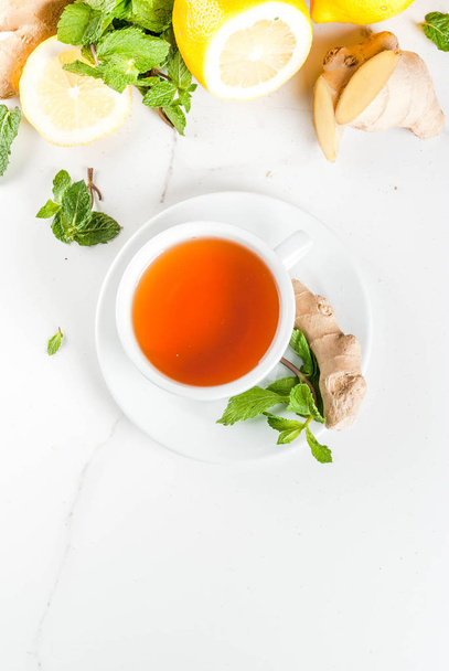 Tasse de thé au gingembre avec citron, menthe fraîche et miel, sur fond blanc
 - Photo, image