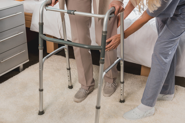 verpleegkundige en senior patiënt met walker - Foto, afbeelding